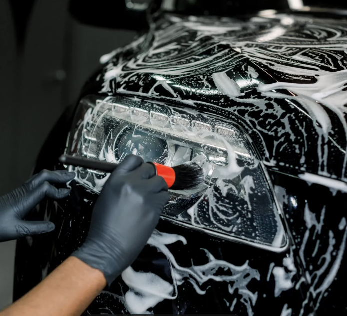 Collection of car cleaning tools and products including wash mitt, towels, and dash duster.