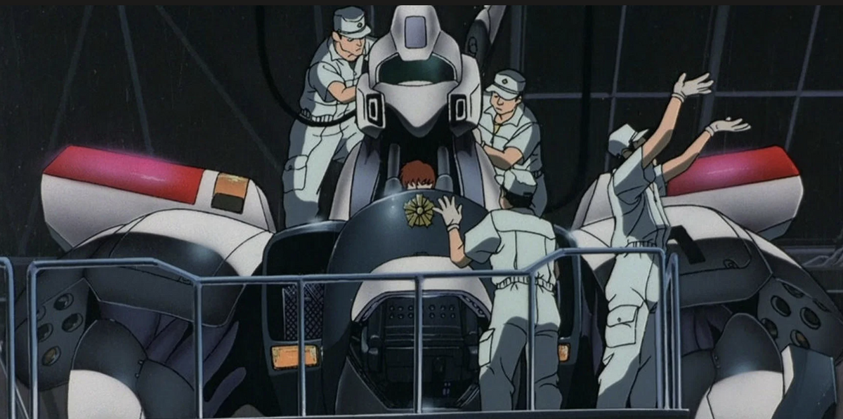 Technicians working on a Patlabor toy collection robot, showcasing detailed engineering and design elements.