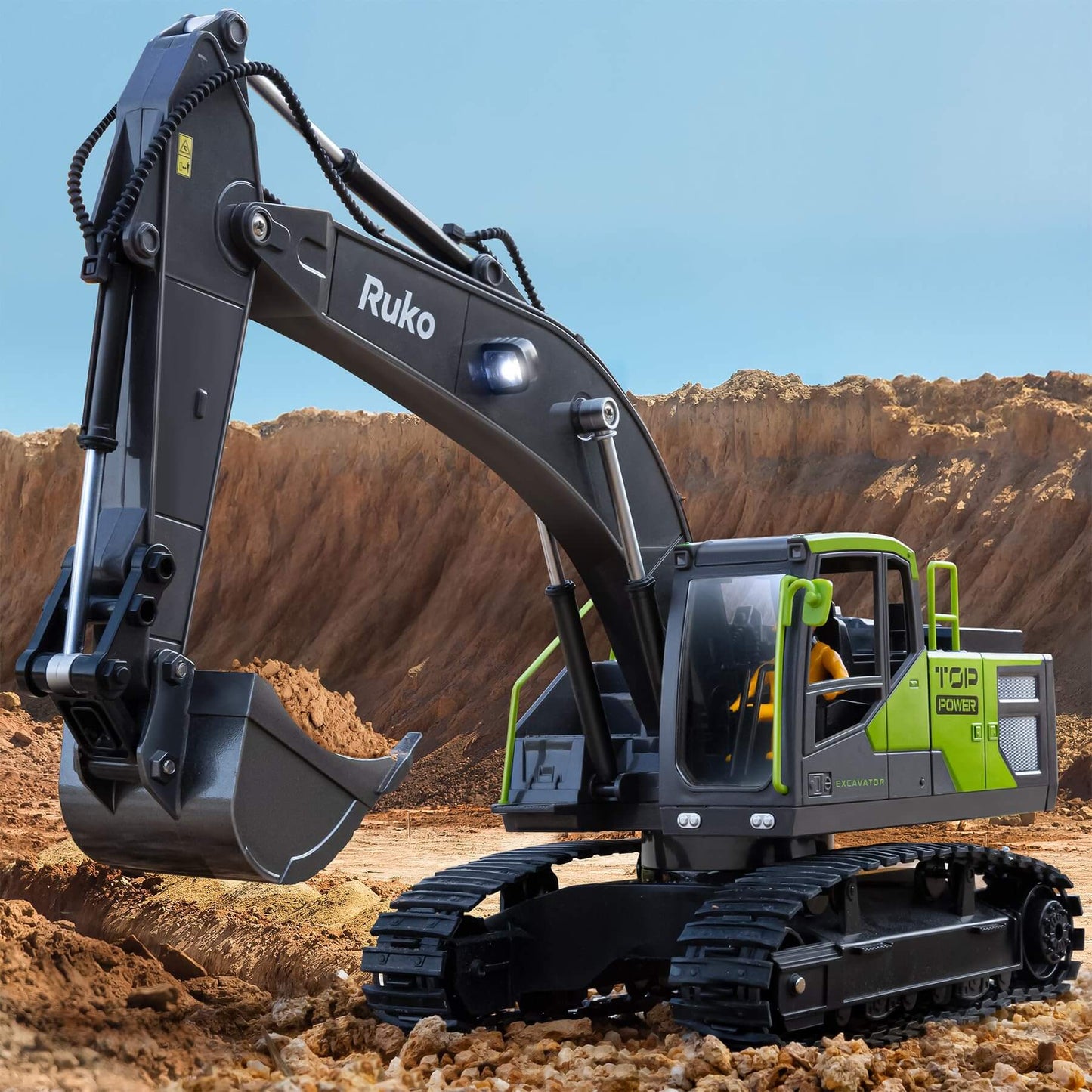 Ruko 1661 remote control excavator toy for boys with metal shovel and simulated lights in action on a dirt landscape.