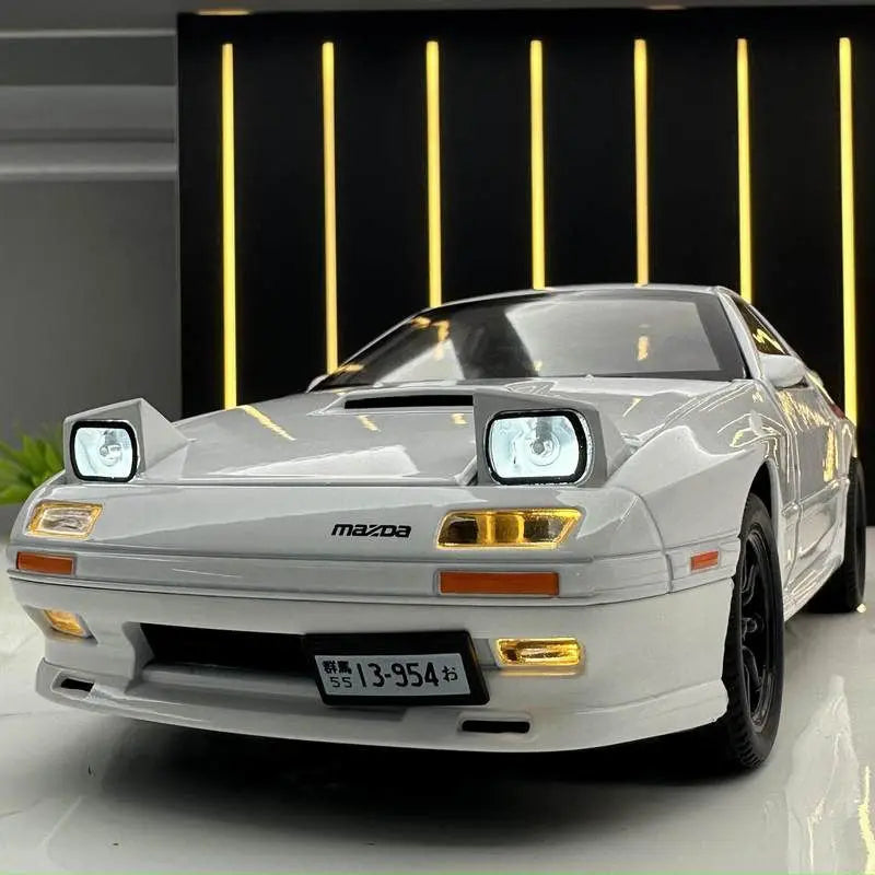 Mazda RX7 diecast model car in white with illuminated headlights on display.