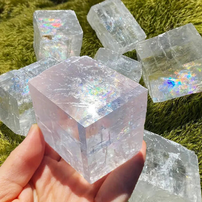 Natural crystal calcite cube ornament held in hand, showcasing rainbow colors and unique mineral texture.