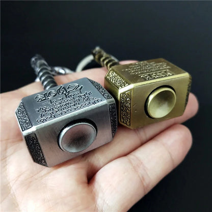 Mjolnir fidget spinner keychain featuring metallic gray and gold hammer designs held in a hand.