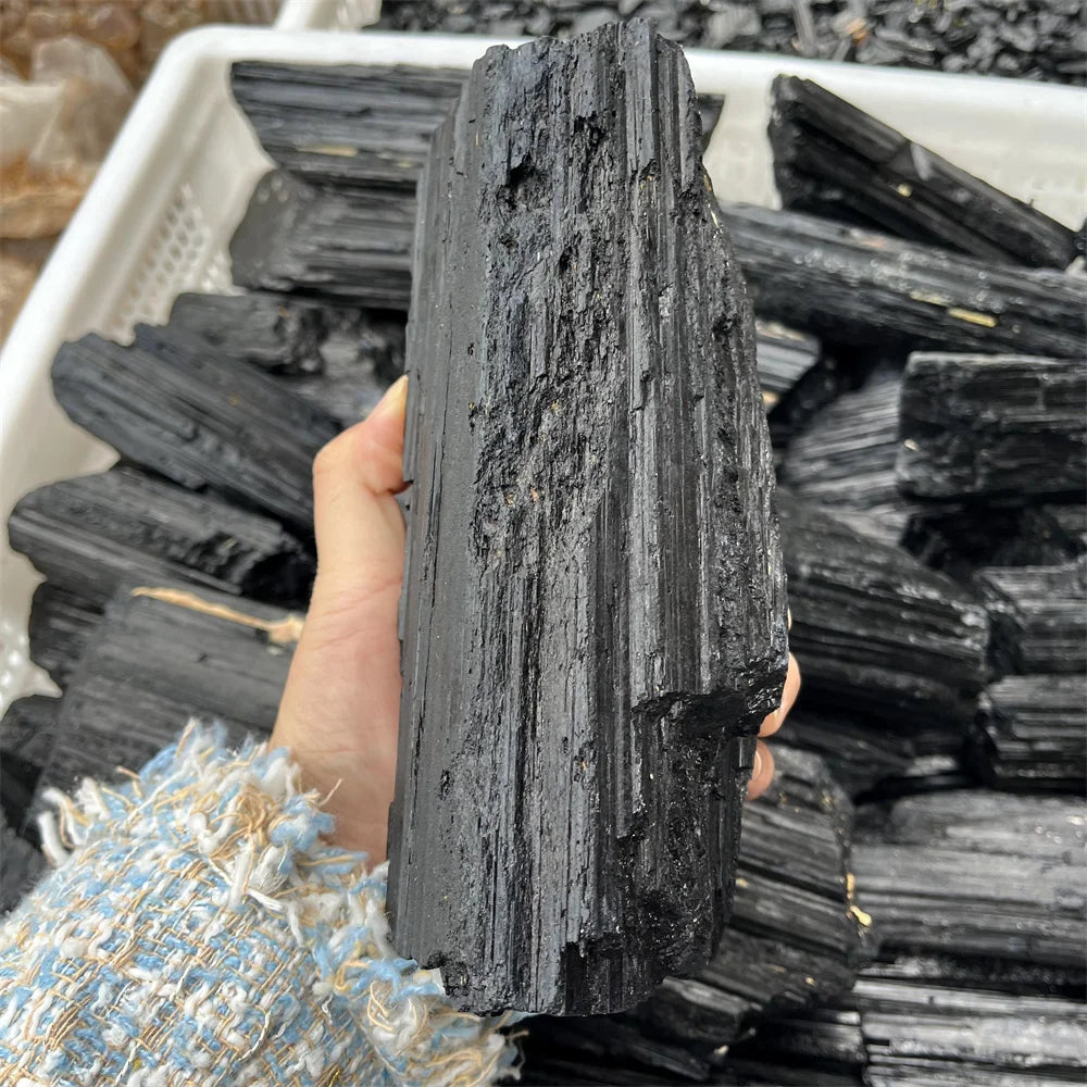 Natural black tourmaline gravel rough mineral held in hand, showcasing its unique texture and healing properties.