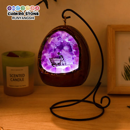 Natural amethyst dinosaur egg lamp illuminating a cozy space on a bedside table.